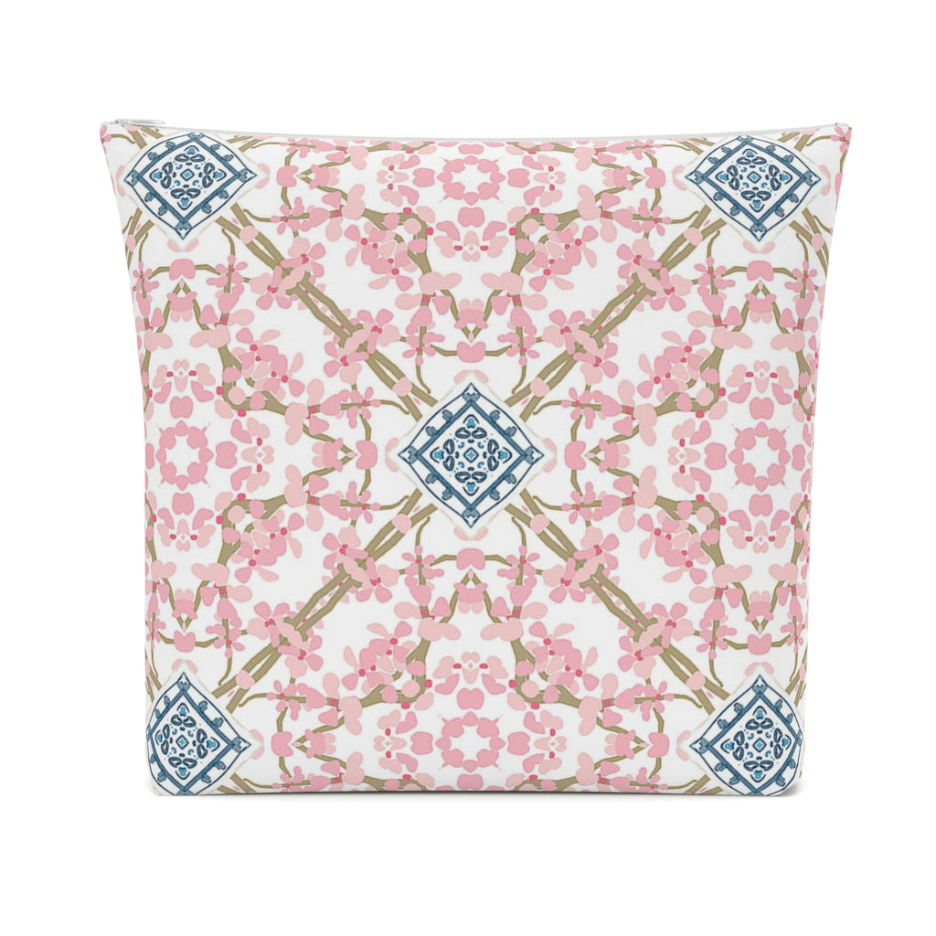 Rectangular cosmetic bag with white zipper and design of pink flowers in a circular pattern with blue and white motif at the center of brown twigs crossing on a white background