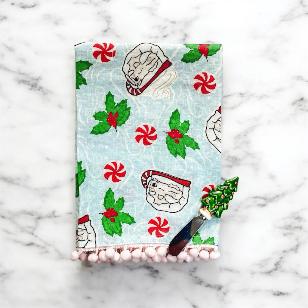 Vintage santa mugs on a tea towel with round peppermint candies and holly branches