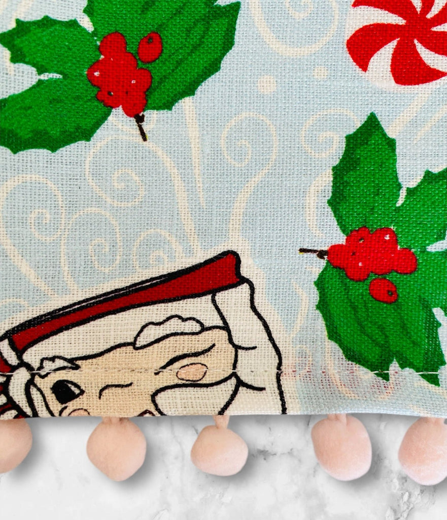 Vintage santa mugs on a tea towel with round peppermint candies and holly branches