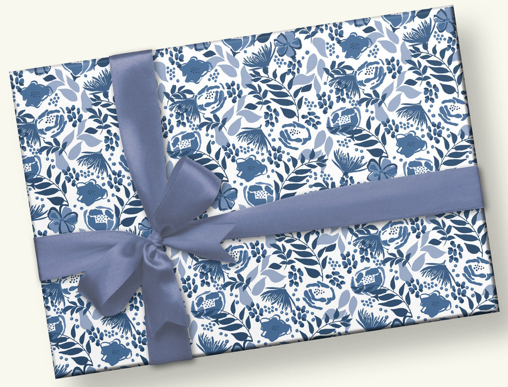 This is a rectangular gift with a grey/blue bow and a hand design of different types of blue flowers and leafy stems.