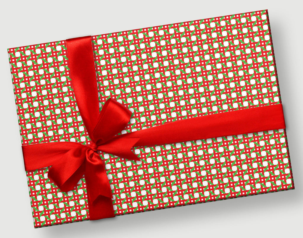 This is a rectangular gift with a red satin bow. The gift wrap pattern is a hand designed caning pattern with intricate geometric designs in shades of red and green